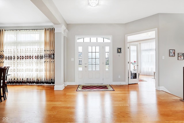 entryway with light wood-type flooring, baseboards, plenty of natural light, and ornate columns