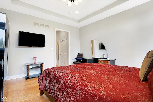 bedroom featuring recessed lighting, visible vents, baseboards, light wood-style floors, and a raised ceiling