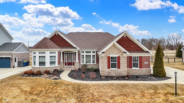 craftsman house with stone siding, a front lawn, roof with shingles, and fence