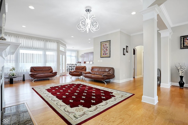 living area featuring arched walkways, ornate columns, ornamental molding, wood finished floors, and baseboards