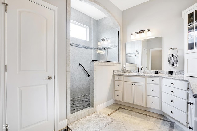 full bathroom with tile patterned flooring, baseboards, a walk in shower, and vanity