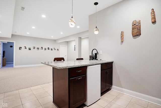 kitchen featuring light stone counters, baseboards, dark brown cabinets, and a sink