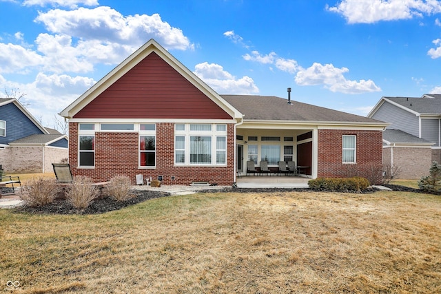 rear view of property featuring a yard, a patio, and brick siding