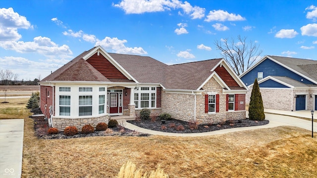 craftsman inspired home featuring stone siding, a front lawn, and a shingled roof