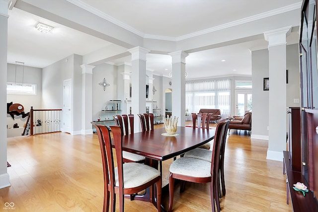 dining space featuring crown molding, light wood-style floors, baseboards, and ornate columns