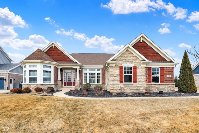 craftsman inspired home featuring stone siding, a front lawn, and roof with shingles