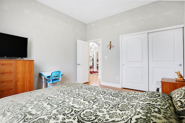 bedroom featuring arched walkways, a closet, baseboards, and wood finished floors