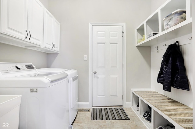 washroom featuring washing machine and dryer, cabinet space, a sink, and baseboards