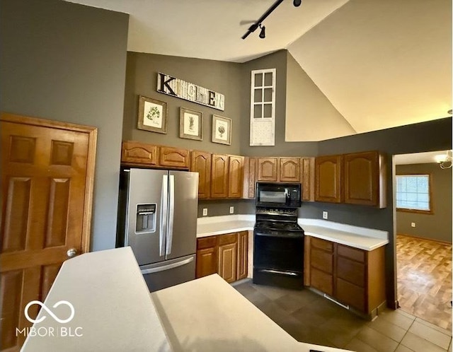 130 Hanover Dr, Morristown, IN 46161 - kitchen featuring black appliances, rail lighting, light countertops, brown cabinetry, and high vaulted ceiling