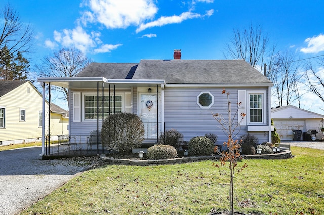 view of front facade featuring a front lawn, a detached garage, a porch, roof with shingles, and a chimney