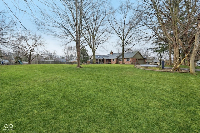 view of yard featuring a playground, a garage, and fence