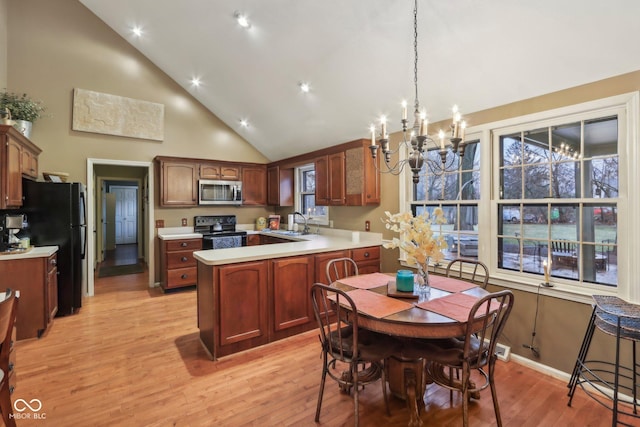 kitchen with light wood-type flooring, light countertops, a peninsula, black appliances, and a sink