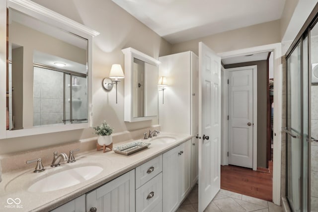 full bath with a sink, a stall shower, and tile patterned floors