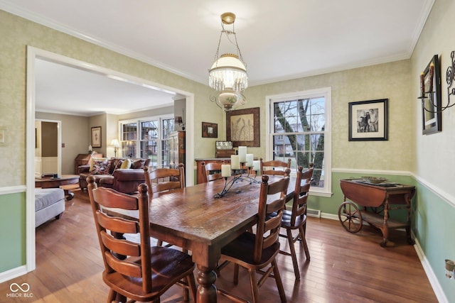 dining area with a notable chandelier, crown molding, baseboards, and hardwood / wood-style floors