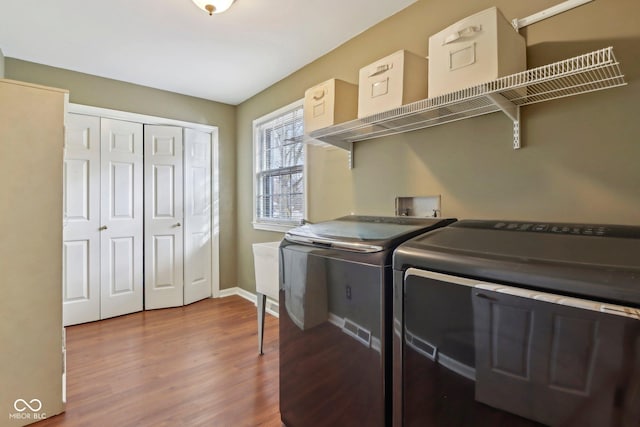 washroom featuring baseboards, wood finished floors, laundry area, and washer and clothes dryer