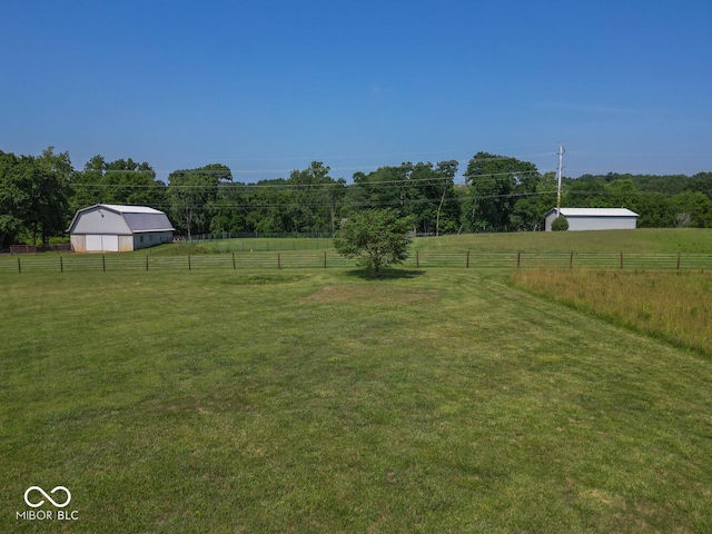 view of yard with an outbuilding, a rural view, and fence