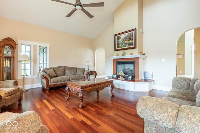 living area featuring baseboards, arched walkways, wood finished floors, and a glass covered fireplace