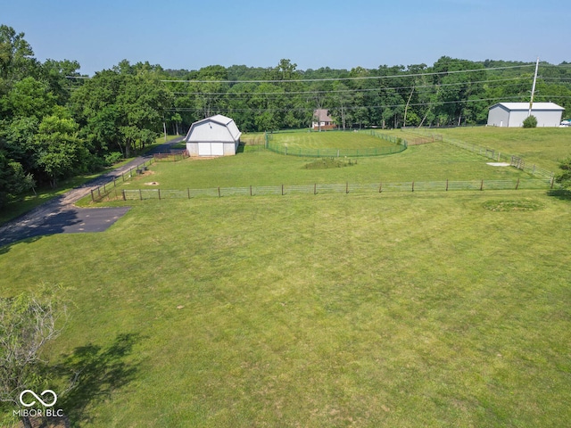 view of yard featuring an outbuilding, a barn, a rural view, and fence