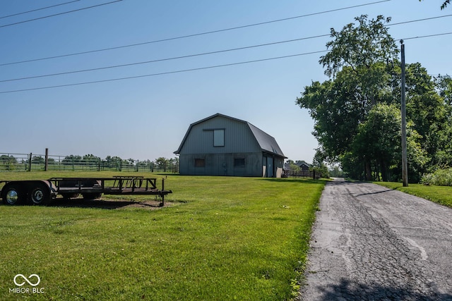 view of front of property featuring a barn, a gambrel roof, fence, an outdoor structure, and a front yard