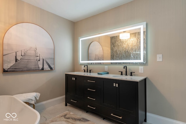 full bath with marble finish floor, a sink, baseboards, and double vanity