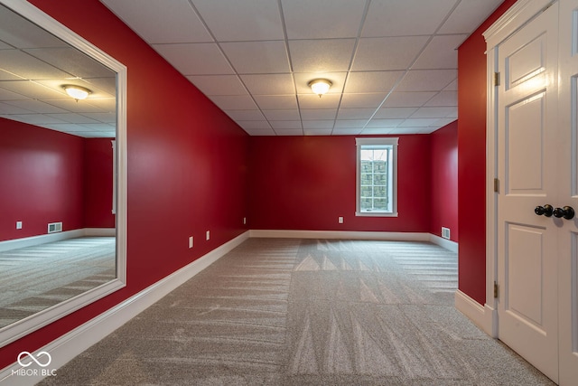 carpeted empty room featuring a paneled ceiling, visible vents, and baseboards