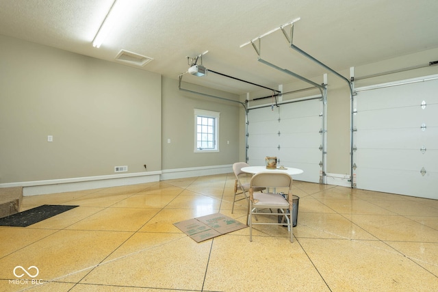 garage with a garage door opener, visible vents, and baseboards