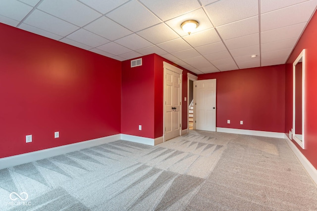 empty room featuring a paneled ceiling, visible vents, stairway, light carpet, and baseboards