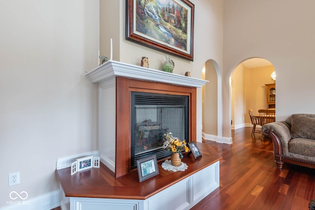 room details featuring arched walkways, a fireplace, baseboards, and wood finished floors