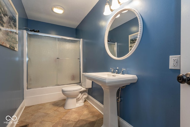 bathroom with toilet, baseboards, and combined bath / shower with glass door