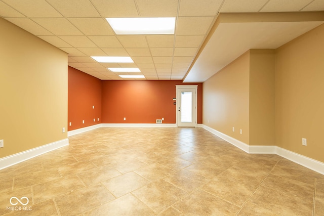 spare room with a paneled ceiling, visible vents, and baseboards