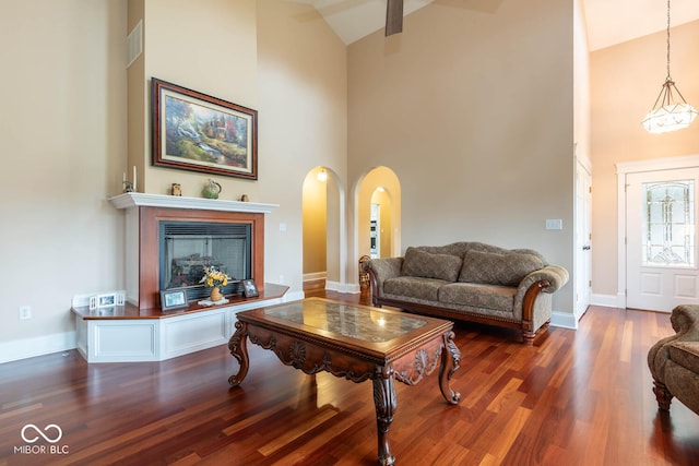 living area with high vaulted ceiling, wood finished floors, visible vents, and baseboards