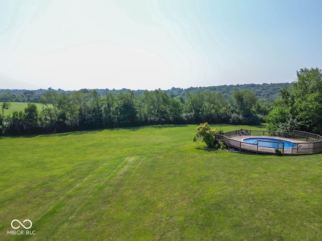 view of yard featuring a forest view and a fenced in pool