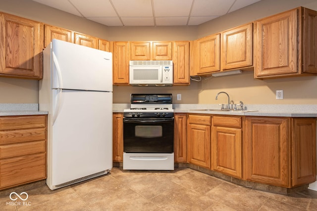 kitchen featuring white appliances, light countertops, a sink, and a drop ceiling