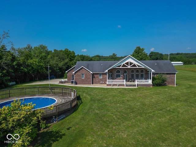 rear view of property featuring a yard, brick siding, and a fenced in pool