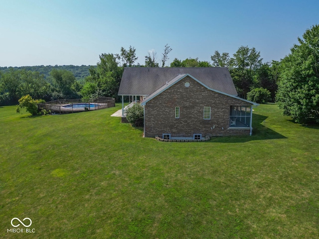 view of side of property with brick siding, a lawn, and a fenced in pool