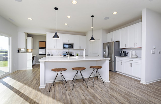 kitchen with light wood-style flooring, white cabinetry, stainless steel appliances, and backsplash