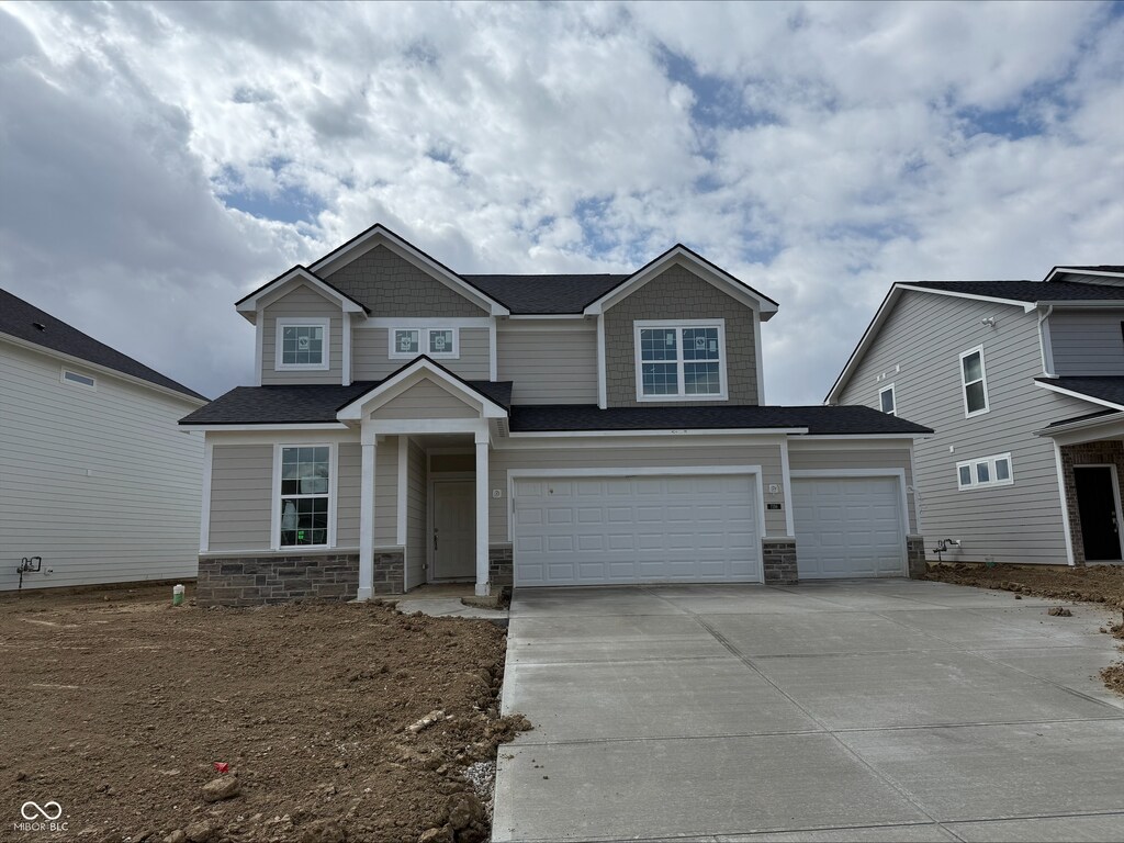 craftsman-style house featuring stone siding, driveway, and an attached garage