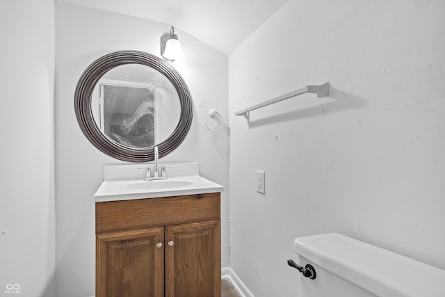 half bath featuring baseboards, vanity, and toilet