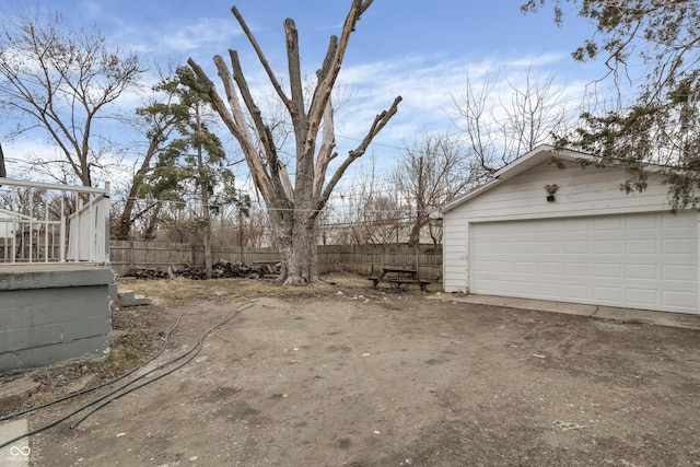 view of yard with a garage, an outbuilding, and fence