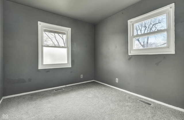 unfurnished room featuring carpet floors, visible vents, and baseboards