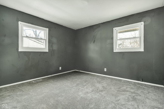 unfurnished room featuring carpet floors, a wealth of natural light, and visible vents