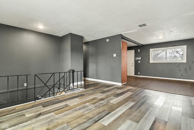 spare room featuring baseboards, visible vents, and wood finished floors