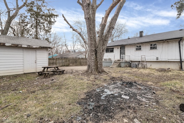 view of yard featuring a storage unit, an outdoor structure, and fence