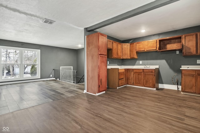 kitchen featuring brown cabinetry, baseboards, visible vents, and dark wood finished floors