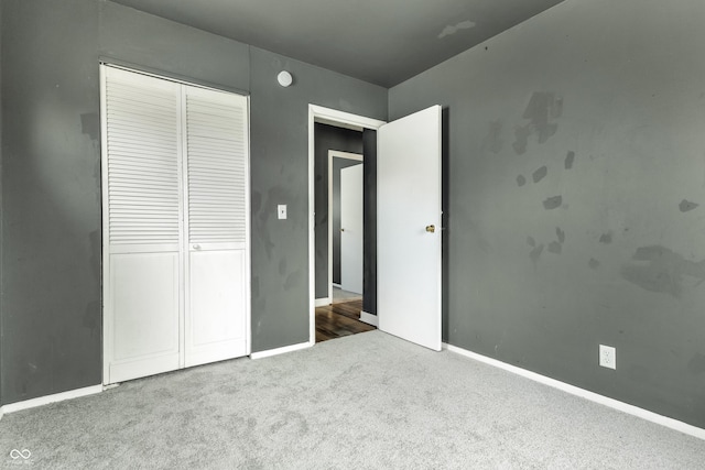 unfurnished bedroom with carpet floors, a closet, and baseboards