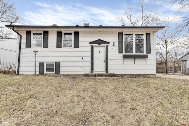 raised ranch featuring fence and a front lawn