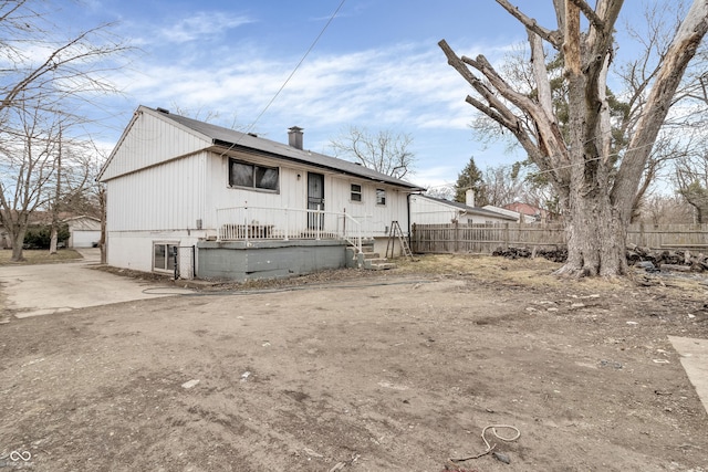 back of house featuring a chimney and fence