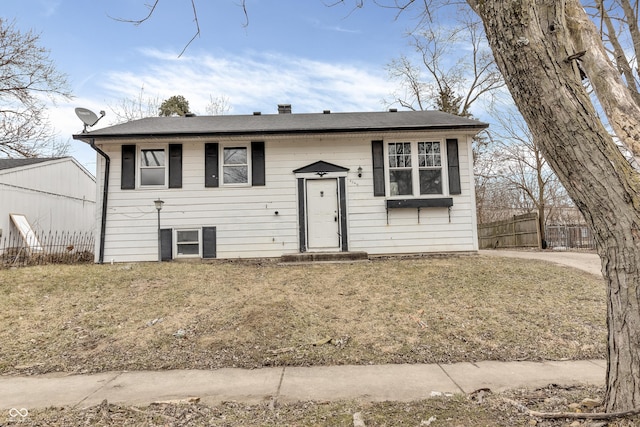 split foyer home featuring a front lawn and fence