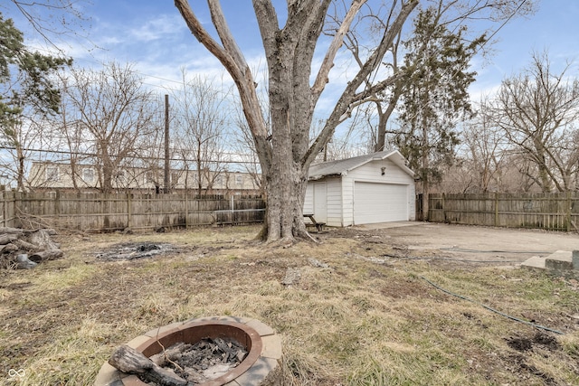 view of yard with an outbuilding, an outdoor fire pit, a fenced backyard, and a garage