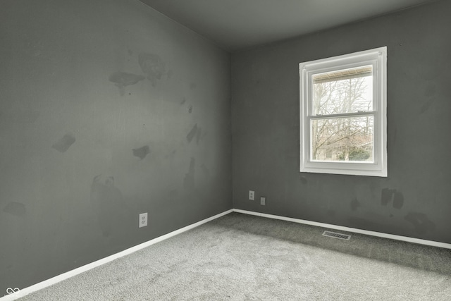 unfurnished room with carpet floors, visible vents, and baseboards